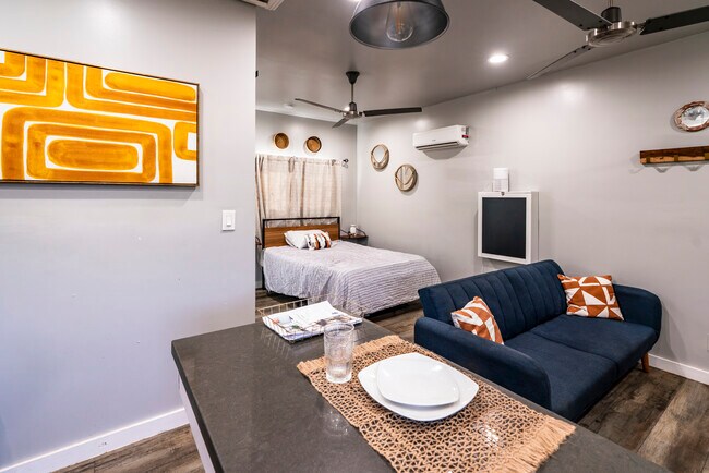 View of living area from kitchen; shows secretary desk (chalkboard wall mount), bed and mini split - 6403 Arlington Ave