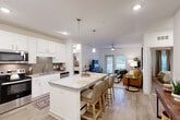 This single-floor, 2-bedroom, 2-bathroom residence in Dalton, GA offers a thoughtfully designed open-concept layout that maximizes both functionality and comfort. The kitchen serves as the heart of the home, showcasing white shaker cabinetry, granite countertops, stainless steel appliances including a French door refrigerator, and a spacious central island with pendant lighting and bar seating — seamlessly connecting to the living and dining areas. The living room is bright and welcoming, featuring wood-look flooring, a ceiling fan, and a glass door that invites natural light and outdoor views. Both bedrooms are carpeted and fitted with ceiling fans and large windows with draping curtains, creating a calm retreat. The primary bedroom connects to a private en-suite bathroom complete with a glass-enclosed shower, granite vanity, wood-look flooring, and direct access to a walk-in closet outfitted with wire shelving. A dedicated laundry room houses a full-size Whirlpool top-load washer and dryer with overhead wire shelving for added storage. Throughout the residence, a neutral color palette and consistent finishes create a cohesive, modern aesthetic suited for everyday living.