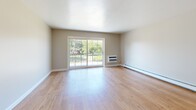 Located at 300 Glen Meadow Rd in Franklin, MA, this one-bedroom, one-bathroom residence offers a well-designed, single-floor layout with a cohesive and functional flow throughout. Light-toned hardwood flooring extends continuously across all living areas, creating a warm and unified aesthetic.

The combined kitchen and living room forms the heart of the home. The living area is bright and open, anchored by large sliding glass doors that lead to a private balcony and frame lush outdoor greenery, flooding the space with natural light. A wall-mounted HVAC unit and baseboard heating ensure year-round comfort. A pass-through window connects the living area to the kitchen, which features warm wood cabinetry, granite-look countertops, a stainless steel electric range, and a built-in microwave — providing a practical and attractive cooking environment.

The bedroom is a comfortable, well-proportioned room with a double window overlooking the outdoors and baseboard heating. It is serviced by a dedicated closet. The bathroom is clean and classic in design, featuring full white tile surround walls, a shower-tub combination, and wood-toned flooring. The entryway area provides additional access points and benefits from overhead lighting, completing this efficiently designed and move-in-ready home.