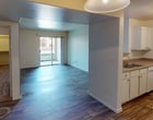 This single-floor residence offers a practical and well-organized layout designed for comfortable everyday living. The open-concept living and dining area is finished with durable wood-style flooring that extends throughout the main living spaces, creating a cohesive and easy-to-maintain environment. Natural light pours in through large sliding glass doors that lead to a private outdoor patio, offering a pleasant connection to the outdoors.

The kitchen is efficiently designed with white cabinetry, laminate countertops, and a full suite of white appliances including a gas range, built-in microwave, refrigerator, and dishwasher. A pendant light fixture and track lighting illuminate the space, while a pass-through opening connects the kitchen to the living area, enhancing the open feel. A dedicated laundry area is conveniently tucked just off the kitchen.

The bedroom is a comfortable, carpeted retreat featuring a ceiling fan with integrated lighting and a window that brings in natural light. The full bathroom includes a soaking tub and shower combination with white and gray tile surround, wood-style flooring, and a vanity with countertop storage. Clean, neutral wall tones throughout the residence provide a versatile backdrop suitable for a variety of interior styles.