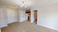 This single-floor apartment offers 710 square feet of well-organized living space across 2 bedrooms and 2 bathrooms. The unit is finished in soft gray tones with clean white trim, creating a calm and neutral aesthetic throughout. Both bedrooms feature wall-to-wall carpet, natural light from windows with blinds, and ample closet space — the primary bedroom measures 180 square feet and includes a double-door closet. The kitchen is equipped with rich warm-toned cabinetry, light countertops, tile flooring, and white appliances including a range, built-in microwave, and dishwasher, alongside a double-basin sink. The two bathrooms share a consistent design with warm wood-toned vanity cabinets, white countertops, tile flooring, and lighted mirrors. Notably, one bathroom is ADA-accessible, featuring multiple grab bars positioned near the toilet and shower for enhanced safety and usability. The overall layout, as seen in the dollhouse view, is compact yet efficiently arranged, with clearly defined rooms and good flow between spaces. This unit is well-suited for those seeking a manageable, accessible living space with practical finishes.
