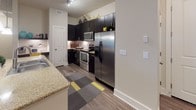 Located at 10270 Commonwealth St in Lone Tree, Colorado, this single-floor residence offers a thoughtfully designed layout with modern finishes and a cohesive aesthetic throughout. The kitchen is a standout feature, showcasing dark espresso cabinetry, granite countertops, a subway tile backsplash, and a full suite of stainless steel appliances including a range, over-the-range microwave, and side-by-side refrigerator. Wood-style flooring grounds the space with warmth and durability. The open living area is bright and welcoming, featuring plush carpeting and large sliding glass doors that invite natural light and provide access to an outdoor patio. A dedicated dining area offers an intimate setting ideal for entertaining. The primary bedroom is generously sized with a ceiling fan, large window, and direct access to an en-suite bathroom featuring a dual-sink vanity with dark cabinetry, granite countertops, a walk-in glass-enclosed shower, and wood-style flooring accented by colorful striped rugs. The second bedroom is equally comfortable, with natural light and a ceiling fan. A second full bathroom includes a soaking tub with tiled surround and dark vanity cabinetry, maintaining the design consistency found throughout the home.