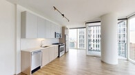 Located on South Michigan Avenue in Chicago's vibrant South Loop neighborhood, this modern one-bedroom, one-bathroom residence offers a sleek, contemporary design throughout. Light hardwood flooring flows seamlessly across the open-concept living and kitchen areas, complemented by crisp white walls that enhance the sense of brightness and space.

The kitchen is thoughtfully appointed with two-tone cabinetry—white upper cabinets paired with warm wood lower cabinets—a tile backsplash, and a full suite of stainless steel appliances including a gas range, built-in microwave, dishwasher, and refrigerator. Track lighting overhead adds a modern finishing touch.

Floor-to-ceiling windows bathe the living area in natural light while framing impressive views of the Chicago skyline. Two private balconies extend the living space outdoors, offering elevated perspectives of the surrounding cityscape. A bright hallway connects the main living areas to the bedroom, which features its own large window with city views and a dedicated closet.

The bathroom is finished with large-format tile flooring, a wood-toned vanity with a white countertop, and a tiled tub surround. Additional conveniences include an in-unit laundry area, completing this well-designed urban residence.