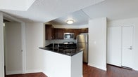 This well-appointed 2-bedroom, 2-bathroom residence offers a practical and inviting layout across a single floor. The kitchen serves as a central highlight, featuring rich dark wood cabinetry, sleek black granite countertops, and a full suite of stainless steel appliances including a gas range, built-in microwave, and refrigerator. A peninsula with an integrated sink provides additional prep space and creates a natural division between the kitchen and the adjoining living area, making it ideal for everyday use and casual entertaining. Warm hardwood flooring extends throughout the main living spaces, adding depth and a cohesive aesthetic to the home. The neutral wall tones complement the darker kitchen finishes, creating a balanced and welcoming atmosphere. A textured ceiling adds a classic residential touch throughout. The open sightlines between the kitchen and living area contribute to an efficient yet comfortable flow, maximizing the use of the available space. With two full bathrooms and two bedrooms, this residence offers functional versatility suited to a variety of living arrangements.