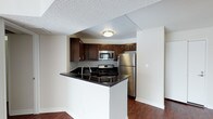 This well-appointed 2-bedroom, 2-bathroom residence offers a practical and inviting layout across a single floor. The kitchen serves as a central highlight, featuring rich dark wood cabinetry, sleek black granite countertops, and a full suite of stainless steel appliances including a gas range, built-in microwave, and refrigerator. A peninsula with an integrated sink provides additional prep space and creates a natural division between the kitchen and the adjoining living area, making it ideal for everyday use and casual entertaining. Warm hardwood flooring extends throughout the main living spaces, adding depth and a cohesive aesthetic to the home. The neutral wall tones complement the darker kitchen finishes, creating a balanced and welcoming atmosphere. A textured ceiling adds a classic residential touch throughout. The open sightlines between the kitchen and living area contribute to an efficient yet comfortable flow, maximizing the use of the available space. With two full bathrooms and two bedrooms, this residence offers functional versatility suited to a variety of living arrangements.