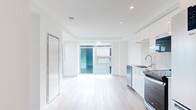 Located at 1470 Queen Street in Halifax, Nova Scotia, this modern 2-bedroom, 2-bathroom unit offers a thoughtfully designed single-level layout with clean architectural lines and a bright, contemporary aesthetic throughout. Light hardwood flooring flows seamlessly across the main living areas, complementing the crisp white walls and recessed lighting that keep the space feeling open and airy.

The open-concept kitchen is a standout feature, showcasing sleek flat-front white cabinetry, a marble-style tile backsplash, stone countertops, and a full suite of stainless steel appliances including a dishwasher, range, over-the-range microwave, and refrigerator. An in-unit stacked washer and dryer adds everyday convenience. The adjacent living area is bathed in natural light from large sliding glass doors that open to an outdoor balcony, offering views of the surrounding cityscape.

Both bedrooms are well-proportioned with large windows that continue to bring in abundant natural light and urban views. The primary bathroom features a soaker tub with a tiled surround and a white vanity with stone countertop, while the second bathroom offers a glass-enclosed walk-in shower and matching vanity. Two hallways and a closet provide practical storage throughout the unit.