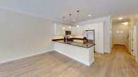 Located in East Amherst, NY, this two-floor home offers a thoughtfully designed layout with clean, modern finishes throughout. The main level centers around an open-concept kitchen and living area, where light hardwood-style flooring flows seamlessly underfoot. The kitchen is a standout feature, equipped with white shaker-style cabinetry, dark granite countertops, stainless steel appliances including a gas range, built-in microwave, and refrigerator, as well as a peninsula with pendant lighting overhead. Crown molding adds a refined touch to the kitchen and living space, which is further complemented by a ceiling fan. A convenient half bath on the main level features a pedestal sink and hardwood-style flooring. Upstairs, the bedrooms are generously sized with plush carpeting and windows that frame views of the surrounding wooded, snow-dusted landscape, filling each room with natural light. The primary bathroom features a walk-in glass shower with white subway tile, a vanity with granite countertops, and chrome fixtures. A secondary full bath offers a tub-shower combination with matching white tile surround. A stacked laundry area is also present, adding everyday practicality. The home's neutral color palette and quality finishes create a bright, welcoming ambiance throughout.