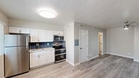 Located at 4301 North 24th Street in Phoenix, AZ, this single-floor unit offers a thoughtfully designed open-concept layout that seamlessly integrates the kitchen and living area into one cohesive space. Light gray walls and wood-style laminate flooring create a clean, modern aesthetic throughout, while white baseboards and trim add a crisp, polished finish.

The kitchen is a standout feature, outfitted with white shaker-style cabinetry, a bold navy blue decorative tile backsplash, and a full suite of stainless steel appliances including a double-oven range, over-the-range microwave, and full-size refrigerator. A single-basin sink is set into light countertops, completing the functional and stylish design.

The living area is open and versatile, benefiting from natural light via a window near the kitchen. A ceiling fan provides comfort, and the neutral color palette allows for flexible furnishing arrangements. HVAC vents and a thermostat indicate climate control throughout the unit.

Additional highlights include a private entry door, an electrical panel conveniently housed within the unit, and access to a bathroom visible through a hallway corridor. The overall ambiance is bright, clean, and move-in ready, reflecting a modern and practical approach to compact urban living in the heart of Phoenix.