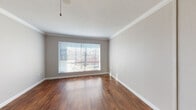This single-floor residence offers a well-organized layout with a variety of thoughtfully designed living spaces. The main living and dining areas are anchored by rich, dark hardwood-style flooring that runs throughout, complemented by crown molding and ceiling fans that add a polished finish. Large windows dressed with horizontal blinds allow generous natural light to fill these open spaces, creating a bright and welcoming ambiance.

A wide hallway connects the main living area to the rest of the home, featuring built-in open shelving on one side — a practical and visually appealing storage solution. The hallway leads to a kitchen equipped with gray cabinetry, a mosaic tile backsplash in warm earth tones, light countertops, a double-basin sink, and white appliances including a range, microwave, and refrigerator.

The bedrooms are carpeted for comfort and each features a ceiling fan with light fixture and windows that bring in natural light. One bedroom includes access to an adjacent room, adding flexibility to the floor plan.

The bathrooms are finished with clean white subway-style tile surrounding full soaking tubs, offering a simple and functional design. Overall, this space presents a practical and comfortable layout with consistent finishes throughout.