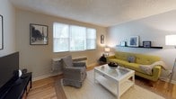 This single-floor residence offers a thoughtfully laid-out living space with warm hardwood flooring and a textured ceiling throughout. The living room is bright and welcoming, featuring large windows with natural light filtering through blinds, and an elegant arched doorway that connects to the hallway, adding a classic architectural touch. The space comfortably accommodates multiple seating areas and provides a relaxed, functional atmosphere.

The kitchen is well-equipped with dark espresso cabinetry, granite countertops, a subway tile backsplash, and stainless steel appliances including a gas range, built-in microwave, and dishwasher. A window above the counter allows natural light to brighten the workspace.

The bedroom is a serene retreat, featuring a ceiling fan with light fixture, a spacious closet with bifold doors, and hardwood flooring. The room offers ample space for a full furniture arrangement and benefits from natural light through a window.

The bathroom showcases a distinctive retro design with mint green and black tile work lining the tub surround and walls, complemented by a clean white vanity and a full tub-shower combination. The mirrored medicine cabinet adds practical storage.

Overall, the residence combines classic architectural details with modern updates, creating a comfortable and functional living environment.