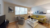 This single-floor residence offers a thoughtfully laid-out living space with warm hardwood flooring and a textured ceiling throughout. The living room is bright and welcoming, featuring large windows with natural light filtering through blinds, and an elegant arched doorway that connects to the hallway, adding a classic architectural touch. The space comfortably accommodates multiple seating areas and provides a relaxed, functional atmosphere.

The kitchen is well-equipped with dark espresso cabinetry, granite countertops, a subway tile backsplash, and stainless steel appliances including a gas range, built-in microwave, and dishwasher. A window above the counter allows natural light to brighten the workspace.

The bedroom is a serene retreat, featuring a ceiling fan with light fixture, a spacious closet with bifold doors, and hardwood flooring. The room offers ample space for a full furniture arrangement and benefits from natural light through a window.

The bathroom showcases a distinctive retro design with mint green and black tile work lining the tub surround and walls, complemented by a clean white vanity and a full tub-shower combination. The mirrored medicine cabinet adds practical storage.

Overall, the residence combines classic architectural details with modern updates, creating a comfortable and functional living environment.