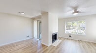 This 2-bedroom, 2-bathroom apartment at 2053 NE 106th Ave in Hillsboro, Oregon offers a practical and comfortable single-floor layout. The living room serves as the heart of the home, featuring light wood-look laminate flooring, a classic fireplace with a clean white surround, a ceiling fan with light fixture, and multiple windows that invite generous natural light and outdoor views. The kitchen is well-appointed with rich, dark wood cabinetry, brushed nickel hardware, crisp white countertops, and a stainless steel sink — offering ample storage and a polished, functional workspace. Both bedrooms are finished with plush neutral carpet, bright white trim, and panel doors, providing a calm and comfortable retreat. The primary bedroom is generously sized with two windows overlooking the surrounding greenery. The two bathrooms each feature a full tub-shower combination with clean white surrounds and brushed nickel fixtures. A dedicated in-unit laundry room accommodates a full-size washer and dryer side by side, complete with a shelf for added convenience. The hallway connects all rooms efficiently, with a closet providing additional storage. Neutral tones and clean finishes throughout create a cohesive and move-in ready environment.