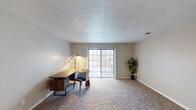 This single-story unit offers a well-organized layout with distinct living, sleeping, and functional zones throughout. The galley-style kitchen is efficiently designed with white cabinetry, granite-look countertops, a stainless steel sink, and black appliances including a range and refrigerator. Light wood-look flooring runs through the kitchen, and a louvered pantry closet provides additional storage.

The living areas feature neutral-toned carpet and textured ceilings, creating a warm and cohesive atmosphere. A spacious main living room benefits from a large sliding glass door that invites natural light and provides outdoor access. A secondary carpeted room, suitable as a bedroom or office, also features a sliding glass door and ample space. Additional carpeted rooms connect through open doorways, offering flexible use and good flow throughout the unit.

The bedrooms are equipped with louvered bifold closet doors and standard carpeting. Two bathrooms serve the unit: one features a wall-mounted sink, toilet, and wood-look flooring, while the other includes a white vanity with an undermount sink, brushed nickel fixtures, a large mirror, and wood-look flooring, providing a clean, functional aesthetic.