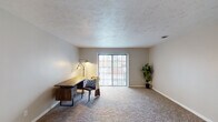This single-story unit offers a well-organized layout with distinct living, sleeping, and functional zones throughout. The galley-style kitchen is efficiently designed with white cabinetry, granite-look countertops, a stainless steel sink, and black appliances including a range and refrigerator. Light wood-look flooring runs through the kitchen, and a louvered pantry closet provides additional storage.

The living areas feature neutral-toned carpet and textured ceilings, creating a warm and cohesive atmosphere. A spacious main living room benefits from a large sliding glass door that invites natural light and provides outdoor access. A secondary carpeted room, suitable as a bedroom or office, also features a sliding glass door and ample space. Additional carpeted rooms connect through open doorways, offering flexible use and good flow throughout the unit.

The bedrooms are equipped with louvered bifold closet doors and standard carpeting. Two bathrooms serve the unit: one features a wall-mounted sink, toilet, and wood-look flooring, while the other includes a white vanity with an undermount sink, brushed nickel fixtures, a large mirror, and wood-look flooring, providing a clean, functional aesthetic.