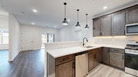 Located at 715 Newark Ave in Elizabeth, NJ, this thoughtfully designed unit offers five bedrooms and two full bathrooms across a single floor. The open-concept kitchen and living area serves as the heart of the space, showcasing rich dark-toned shaker cabinetry, white quartz countertops, a subway tile backsplash, and a peninsula with pendant lighting overhead. Stainless steel appliances, including a gas range, over-the-range microwave, dishwasher, and refrigerator, complete the kitchen. Light-toned wood-style flooring runs throughout the living areas, complementing the bright white walls and recessed lighting. The living room offers sliding glass door access to an outdoor balcony, filling the room with natural light. The bedrooms are well-proportioned, featuring hardwood-style floors, recessed lighting, and large windows. The primary bedroom provides a comfortable and private retreat. Both bathrooms are finished with marble-style tile flooring, dark wood vanities with white quartz countertops, backlit mirrors, and matte black hardware. One bathroom features a glass-enclosed tub-shower combination with elegant marble-look tile surround. The unit also includes two hallways connecting the layout efficiently throughout.