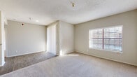 This single-story, 1-bedroom, 1-bathroom unit offers a practical and comfortable layout across a thoughtfully organized floor plan. The entrance leads into a hallway connecting the home's key spaces. The living room is generously proportioned, featuring neutral-toned carpet, soft beige walls, a textured ceiling, and a large window fitted with horizontal blinds that allows ample natural light to fill the room. Vertical blinds on a sliding door provide access to the outdoors. The kitchen is well-equipped with white shaker-style cabinetry, granite-look countertops, a classic subway tile backsplash, and black appliances including an electric range, built-in microwave, refrigerator, and dishwasher. A peninsula counter provides additional workspace and separates the kitchen from the adjacent areas. Wood-look flooring runs through the kitchen and wet areas, adding a clean, cohesive aesthetic. The bedroom is a comfortable size, featuring plush carpeting, dual windows that invite natural light, a ceiling fan, and a dedicated closet. The bathroom includes a full tub-and-shower combination with white tile surround, wood-look flooring, and clean, simple fixtures. A separate laundry area and hallway closet round out this efficiently designed home.