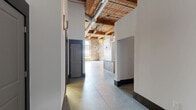 Located at 300 S Firestone St in Gastonia, NC, this industrial-style loft blends historic character with modern finishes across a single open floor plan. The space is defined by striking exposed brick walls, soaring ceilings with original wood beam construction, and polished concrete floors throughout, creating a bold and airy atmosphere.

Oversized multi-pane factory windows flood the main living area with abundant natural light, highlighting the architectural details at every turn. A standout red barn door adds a dramatic focal point against the raw brick backdrop, while exposed ductwork and ceiling fans reinforce the industrial aesthetic.

The well-appointed kitchen features warm wood cabinetry, granite countertops, stainless steel appliances including a range, microwave, dishwasher, and refrigerator, along with a central island that provides additional workspace and seating. A farmhouse-style sink completes the functional layout.

Two bathrooms offer clean, modern finishes consistent with the rest of the space. One bathroom includes a full tub-shower combination, wood vanity with granite countertop, and a large mirror, while the second bathroom features a similar vanity and granite countertop. A hallway connects the private areas to the expansive main living space, ensuring a smooth and practical flow throughout.