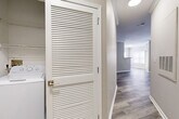 This single-story, 2-bedroom, 2-bathroom residence offers a practical and comfortable layout designed for everyday living. The kitchen is a standout feature, equipped with white cabinetry, granite-style countertops, stainless steel appliances including a range, microwave, and dishwasher, and durable wood-style flooring that extends into the main living areas. Crown molding adds a refined architectural touch throughout the common spaces, enhancing the overall sense of polish and detail.

The primary bedroom is generously sized, featuring soft carpet, neutral-toned walls, and a dedicated closet with wire shelving for organized storage. The second bedroom mirrors a similar aesthetic with plush carpeting, natural light from a window, and its own closet. Both rooms offer a calm, neutral palette suited to a variety of furnishing styles.

The bathrooms are finished with light tile flooring, white vanities with granite-style countertops, and a soaking tub with white tile surround accented by a classic navy border tile detail. A convenient in-unit laundry closet with louvered doors houses a full-size washer and provides added functionality. The overall ambiance is clean, neutral, and move-in ready, combining practical design with comfortable, everyday livability.