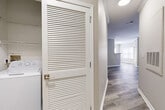 This single-story, 2-bedroom, 2-bathroom residence offers a practical and comfortable layout designed for everyday living. The kitchen is a standout feature, equipped with white cabinetry, granite-style countertops, stainless steel appliances including a range, microwave, and dishwasher, and durable wood-style flooring that extends into the main living areas. Crown molding adds a refined architectural touch throughout the common spaces, enhancing the overall sense of polish and detail.

The primary bedroom is generously sized, featuring soft carpet, neutral-toned walls, and a dedicated closet with wire shelving for organized storage. The second bedroom mirrors a similar aesthetic with plush carpeting, natural light from a window, and its own closet. Both rooms offer a calm, neutral palette suited to a variety of furnishing styles.

The bathrooms are finished with light tile flooring, white vanities with granite-style countertops, and a soaking tub with white tile surround accented by a classic navy border tile detail. A convenient in-unit laundry closet with louvered doors houses a full-size washer and provides added functionality. The overall ambiance is clean, neutral, and move-in ready, combining practical design with comfortable, everyday livability.