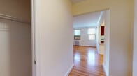 This single-floor residence offers a thoughtfully laid-out interior finished with warm hardwood flooring throughout the main living areas and bedrooms. The open hallway leads into a bright living space illuminated by multiple windows that frame natural outdoor views, while a radiator and window-mounted air conditioning units provide year-round climate control. Crown molding adds a classic architectural detail to the ceilings, lending a refined character to each room.

The kitchen is well-appointed with rich dark wood cabinetry, granite-style countertops, a gas range, built-in microwave, dishwasher, and a stainless steel sink — all set against light tile flooring. A window above the countertop brings in additional natural light and street views.

The bedrooms are generously proportioned, each featuring hardwood floors, crown molding, and window-mounted AC units. One bedroom includes a ceiling fan and dual windows for enhanced ventilation and light, while another offers a closet with built-in shelving and direct access to the hallway.

The full bathroom is clean and classic, featuring white subway tile surrounding a shower-tub combination, a wood-vanity with a light countertop, and a window for natural ventilation. The tile flooring completes the crisp, functional aesthetic of this well-kept home.