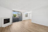 Located at 7011 Woodley Ave in Van Nuys, Los Angeles, this well-appointed 2-bedroom, 2-bathroom single-floor unit offers a clean, modern aesthetic throughout. Light wood laminate flooring flows seamlessly across the entire space, complemented by crisp white walls and textured ceilings that lend a bright, airy feel.

The open living room is a standout, featuring a classic white brick fireplace and floor-to-ceiling sliding glass doors that open to a balcony, filling the room with natural light and outdoor views. An adjacent window adds to the bright ambiance.

The kitchen is thoughtfully designed with white shaker-style cabinetry, light stone countertops, and a full suite of stainless steel appliances including a gas range, microwave, refrigerator, and dishwasher. A window above the sink brings in additional natural light.

Both bedrooms are generously proportioned with large windows dressed in horizontal blinds. The spacious primary bedroom includes mirrored sliding closet doors. Each bathroom is finished in neutral tones, with one featuring a full soaking tub and shower combination with glass block accent windows, and the other offering a vanity with white cabinetry. Two hallways provide convenient connectivity throughout the layout.