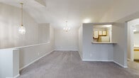 This two-floor home offers a thoughtfully laid-out interior with a blend of functional design and comfortable living spaces. The upper level is highlighted by dramatic vaulted ceilings that soar overhead, creating an airy, open atmosphere in the main living and dining areas. Plush wall-to-wall carpeting runs throughout, adding warmth underfoot, while neutral-toned walls provide a versatile backdrop. A elegant chandelier anchors the dining area, and a pass-through opening connects it seamlessly to the kitchen, enhancing the open-concept feel. A striking arched window at the upper level floods the space with natural light.

The kitchen is well-appointed with white cabinetry trimmed in warm wood accents, offering generous storage through both upper and lower cabinets. Light-toned countertops provide ample prep space, complemented by a stainless steel double-basin sink, an electric range, and a refrigerator. Light wood-look flooring ties the kitchen together with a clean, practical finish.

The bathroom features wood-look flooring, a single vanity with a large mirror, and a full tub-shower combination. The bedrooms are carpeted and bright, with easy access to closet space. A staircase connects the two floors, completing this well-organized, multi-level home.