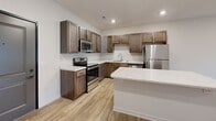 Located at 1220 W Highland Blvd in Lincoln, Nebraska, this single-floor, one-bedroom, one-bathroom unit offers a thoughtfully designed layout with modern finishes throughout. The open-concept living and kitchen area serves as the heart of the home, featuring light-toned luxury vinyl plank flooring, recessed lighting, and a sliding glass door that allows natural light to pour into the living space. The kitchen is a standout, outfitted with rich, dark-stained cabinetry, quartz countertops, a full suite of stainless steel appliances including a range, microwave, dishwasher, and refrigerator, and a peninsula island that provides additional prep and seating space. The bedroom is a comfortable retreat finished with plush carpet, a ceiling fan, a window with exterior views, and access to two closets for ample storage. The full bathroom is clean and functional, featuring a tub-shower combination, a single vanity with quartz countertop, a large mirror, and matching cabinetry consistent with the rest of the unit. Neutral wall tones and consistent finishes throughout give the space a cohesive, contemporary feel. Two closets offer practical storage solutions to complement the well-utilized floor plan.