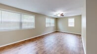 Located at 1420 Marbee Dr #1 in Omaha, Nebraska, this single-floor, one-bedroom, one-bathroom unit offers a practical and comfortable layout across a compact yet efficient floor plan. The living room is bright and welcoming, featuring warm hardwood-style flooring, neutral beige walls, and multiple windows fitted with blinds that allow generous natural light. A ceiling fan adds both function and character to the space. The kitchen is efficiently designed with white cabinetry, ample upper and lower storage, a double sink positioned beneath a window, and white appliances including a refrigerator and range. Hardwood-style flooring continues seamlessly throughout the main living and kitchen areas. The bedroom offers plush carpeting underfoot, a ceiling fan with light fixture, a window for natural light, and a spacious double-door closet providing substantial storage. The bathroom features a rich wood-toned vanity with a large white countertop, an oversized mirror, and clean white finishes throughout. A connecting hallway with louvered closet doors provides additional storage and links the rooms cohesively. The unit's consistent neutral palette and clean finishes create a calm, move-in-ready atmosphere suitable for comfortable everyday living.