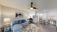 Located at 7595 Baymeadows Cir W in Jacksonville, Florida, this single-floor residence offers a thoughtfully designed open-concept layout that seamlessly connects the living, dining, and kitchen areas. The living room features wood-look flooring, a ceiling fan, and a neutral color palette that creates a warm, inviting atmosphere. A wide entryway leads into the space, where large windows allow natural light to fill the room.

The kitchen is a standout feature, showcasing white shaker cabinetry, a classic subway tile backsplash, stainless steel appliances including a refrigerator, range, and microwave, and a peninsula with quartz countertops and an undermount sink with a matte black faucet. The peninsula doubles as a breakfast bar, connecting the kitchen to the dining area for easy entertaining.

The bedroom is generously sized with plush carpeting, multiple windows that bring in ample natural light, and a ceiling fan overhead. It includes direct access to a private bathroom, which is finished with white cabinetry and modern fixtures.

Throughout the home, the consistent use of light tones, updated finishes, and functional design choices contribute to a clean, contemporary aesthetic that is both practical and comfortable.