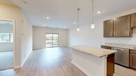 Located at 903 Main Street in Mukwonago, Wisconsin, this well-appointed one-bedroom unit offers a thoughtfully designed layout across a single floor. The open-concept living and kitchen area is bright and airy, featuring light-toned luxury vinyl plank flooring, recessed lighting, and a neutral color palette throughout. The kitchen is a standout feature, equipped with rich dark-wood cabinetry, granite countertops, a breakfast bar with pendant lighting, and a full suite of stainless steel appliances including a range, microwave, and refrigerator. A sliding glass door in the living area opens to a private balcony with views of the surrounding Mukwonago streetscape and green spaces. The generously sized primary bedroom is finished with plush carpeting, a large window that brings in natural light, and access to two closets, including a walk-in closet with built-in shelving and hanging rods. Additional practical features include an in-unit laundry area. Clean lines, modern finishes, and a functional floor plan make this unit a comfortable and stylish living space in a convenient Main Street location.