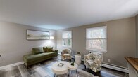 Located at 161 Foster Dr in Willimantic, CT, this well-appointed one-bedroom, one-bathroom residence offers a thoughtfully designed single-floor layout with a warm, neutral color palette throughout. The living room is a welcoming centerpiece, featuring durable hardwood-style flooring, large windows that frame views of the surrounding greenery, and a natural flow from the entryway — which is accented by a round mirror and console table — to the main living and dining areas. Multiple closets provide an impressive amount of storage, keeping the living spaces clean and functional. The galley-style kitchen is efficiently organized with white cabinetry, stainless steel appliances including a range, microwave, and refrigerator, a mosaic tile backsplash, and a window that brings in natural light. The bedroom offers a comfortable retreat with plush carpeting, a window overlooking outdoor greenery, and closet access. The full bathroom includes a tiled tub-shower combination. Throughout the home, consistent warm-toned walls, clean white trim, and cohesive finishes create a unified and inviting ambiance, making this a practical and comfortable residence in the heart of Connecticut.