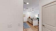 Located at 3171 US-280 E in Birmingham, Alabama, this single-floor residence offers a thoughtfully designed layout with modern finishes and a clean, contemporary aesthetic. The kitchen is a standout feature, showcasing gray shaker-style cabinetry, dark granite countertops, stainless steel appliances, and a central island with pendant lighting. Light wood-style flooring runs throughout, tying the spaces together cohesively. The living area is bright and welcoming, with large windows and a glass-panel door that invite natural light and provide views of the surrounding greenery. A ceiling fan adds comfort, while the open layout creates an easy flow between the living and kitchen areas. The bedroom is generously proportioned, featuring large windows, a ceiling fan, and direct access to the en-suite bathroom. The bathroom is well-appointed with gray cabinetry, a dual-sink vanity topped with dark stone countertops, a frameless glass walk-in shower with white tile surround, and light tile flooring. Additional doors from the bathroom connect to the bedroom and hallway, enhancing the functional layout. Overall, the space presents a polished, move-in-ready residence with modern design elements and practical living spaces.