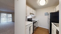 This 1-bedroom, 1-bathroom unit is thoughtfully laid out across a single floor, making efficient use of its space. The combined kitchen and living room area serves as the heart of the home. The living room features neutral-toned carpet, a ceiling fan with light fixture, and a sliding glass door dressed with vertical blinds that invites natural light and provides outdoor access. A pass-through window connects the living area to the kitchen, enhancing the open feel between the two spaces. The kitchen is equipped with stainless steel appliances including an electric range and refrigerator, complemented by white cabinetry, light countertops, an under-cabinet range hood, and warm hardwood-style flooring. The generously sized bedroom offers plush carpeting, neutral walls, a textured ceiling, and a window with outdoor views, creating a calm and restful environment. A closet is accessible directly from the bedroom. The bathroom features a full tub/shower combination with white tile surround, chrome fixtures, and hardwood-style flooring. A hallway connects the main living areas to the bedroom and bathroom, providing a clear and practical flow throughout the unit.