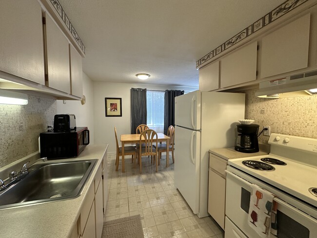 Full kitchen with large sized refrigerator, four burner stove and all dining & cookware - Avalon Suites Apartments