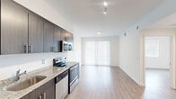 Located at 2201 N Australian Ave in West Palm Beach, Florida, this 2-bedroom, 1-bathroom residence offers a clean, modern aesthetic throughout its thoughtfully designed single-floor layout. The open-concept living, dining, and kitchen area serves as the heart of the home, featuring light wood-style flooring and a bright, neutral color palette that creates an airy, welcoming atmosphere. Large sliding glass doors flood the living area with natural light and provide access to the outdoors.

The kitchen is well-appointed with dark espresso-toned cabinetry extending to the ceiling for maximum storage, granite countertops, a stainless steel sink, and a full suite of stainless steel appliances including a range, microwave, and dishwasher.

Both bedrooms are bright and well-proportioned, each featuring natural light from large windows fitted with blinds and generous closet space with louvered bi-fold doors. Three total closets throughout the unit provide ample storage.

The bathroom is finished with large-format neutral tile surrounding a soaking tub and shower combination, complemented by a window for natural ventilation. Additional conveniences include an in-unit laundry area and a connecting hallway that organizes the private spaces efficiently.