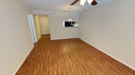 This single-story residence offers a practical and well-appointed layout designed for comfortable everyday living. The main living and dining area is finished with warm wood-style flooring and features a ceiling fan with integrated lighting overhead. A pendant light fixture marks the dining space, which is positioned adjacent to a pass-through kitchen opening — a functional detail that connects the kitchen to the living area while maintaining a sense of defined space. Natural light enters through blinded windows, contributing to a bright and airy atmosphere.

The kitchen is equipped with dark cabinetry, a black electric range with coil burners, a matching refrigerator, and a range hood, all supported by light countertops. A window within the kitchen allows additional natural light into the cooking space.

The bedroom features plush carpeting, a ceiling fan, and a wide window that brings in ample natural light. A closet with built-in shelving and hanging storage is accessible nearby. The bathroom includes a full tub-shower combination, dark wood-toned vanity cabinetry, a single sink, and a large mirror, all laid over wood-style flooring that ties cohesively to the rest of the unit.