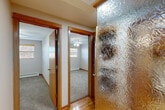 Located at 4802 Regent St in Madison, WI, this single-floor home offers four bedrooms and one bathroom within a compact, efficiently arranged floor plan. The combined kitchen and living area serves as the heart of the home, with the kitchen showcasing warm wood cabinetry, dark countertops, stainless steel appliances including a range, microwave, and refrigerator, and tile flooring. A peninsula provides additional counter space and a natural transition into the dining and living areas, which feature gleaming hardwood floors and large windows fitted with wood-toned blinds that invite natural light. A decorative textured glass panel adds a distinctive architectural touch near the hallway entrance. The four bedrooms are carpeted for comfort, with several rooms featuring ceiling fans and windows that provide natural light and ventilation. Baseboard heating is present throughout. The bathroom is clean and functional, featuring a single-sink vanity with a wood cabinet base and a full tub/shower combination. The overall aesthetic is practical and well-maintained, with consistent warm wood trim details tying the spaces together throughout the home.