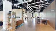 Located on Payne Street in Dover, NH, The Truette & Perch Cowork is a thoughtfully designed, single-floor commercial workspace spanning a generous footprint of nearly 6,000 square feet. The space blends industrial and contemporary aesthetics, featuring polished concrete floors, exposed black-painted ceilings with visible ductwork, and large black-framed windows that invite abundant natural light and views of the surrounding greenery.

At the entrance, a sleek wooden reception desk anchors the arrival experience beneath the co-branded signage of The Truette and Perch Cowork. The open lounge area offers a warm communal atmosphere, complete with a linear fireplace, wood-paneled accent wall, plush seating, and built-in banquette booths for informal gatherings or focused work.

A café-style commons area features dining tables with bench seating set against teal accent walls and curated wall art, offering a casual breakout space. A well-appointed kitchenette provides stone countertops, warm wood floating shelves, and a full-service sink station.

Private offices and focus rooms line the hallways, enclosed by full-height glass partitions and black metal frames. Open workstations with acoustic desk dividers offer collaborative yet focused environments. Throughout, the layout supports a variety of work styles, making this a highly functional and visually compelling professional environment.