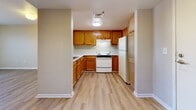 Located at 3280 N Downing St in Denver's Cole neighborhood, this one-bedroom, one-bathroom unit offers a practical and efficiently designed single-floor layout. The open-concept living area flows seamlessly into the kitchen, which features a pass-through counter that connects the two spaces. The kitchen is outfitted with warm oak cabinetry offering generous upper and lower storage, a white range, refrigerator, and a sink, all set on light hardwood-style flooring that extends throughout much of the unit. The living area is carpeted and receives natural light through a window visible from the kitchen pass-through. The bedroom is a well-proportioned, private retreat with a large window that allows ample natural light and views of the surrounding neighborhood, complemented by the same light hardwood-style flooring. Adjacent to the bedroom is a dedicated closet with built-in shelving, providing organized storage. The bathroom is spacious and thoughtfully designed with accessibility in mind, featuring grab bars near the toilet and along the walls, a wood-toned vanity with a white countertop, and matching hardwood-style flooring. The unit's neutral warm-toned walls throughout create a cohesive and inviting atmosphere.