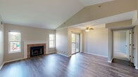 Located at 2302 South Goebbert Road in Arlington Heights, IL, this 2-bedroom, 2-bathroom single-floor home offers a well-designed layout across a comfortable footprint. The open living area immediately impresses with its dramatic vaulted ceilings, which lend an airy, spacious feel to the room. A brick-surround fireplace serves as a focal point, complemented by large windows that flood the space with natural light and provide pleasant outdoor views. Gleaming hardwood-style flooring runs throughout the living area, while a ceiling fan adds both style and function. Sliding glass doors lead to a private balcony, seamlessly connecting indoor and outdoor living. The kitchen features a peninsula counter, white cabinetry, and appliances, with convenient access to an in-unit laundry area. The two bedrooms are carpeted for comfort, each offering windows with outdoor views and ample closet space — including a walk-in closet with built-in shelving in the primary bedroom. Both bathrooms are well-appointed, with one featuring a full tiled tub-shower combination, wood-style flooring, and a vanity with countertop space. A connecting hallway ties all rooms together, creating a practical and cohesive flow throughout the home.