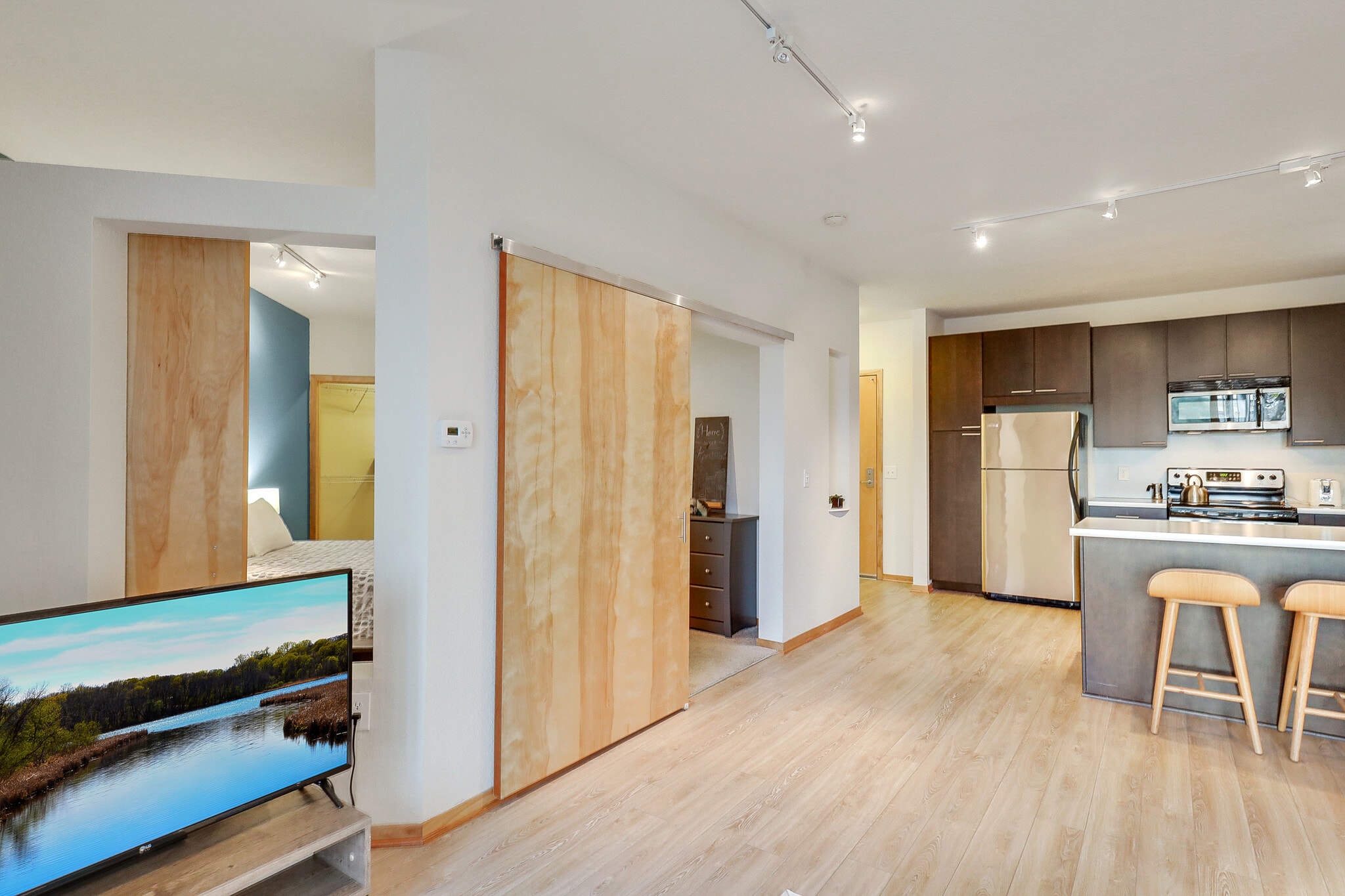 Living room and kitchen area with sliding barn door to bedroom