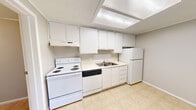 Located at 6041 Ullyot Dr in Fort Wayne, Indiana, this efficiently designed one-bedroom, one-bathroom unit offers a practical and functional single-floor layout. The open-concept living area features neutral-toned carpet and a textured ceiling, creating a clean and understated atmosphere. A distinctive pass-through with built-in shelving connects the living space to the kitchen, enhancing the sense of openness. The kitchen is outfitted with white cabinetry extending to the ceiling for ample storage, light countertops, a stainless steel sink, and a full suite of white appliances including an electric range, dishwasher, and refrigerator. Tile flooring and a recessed ceiling light fixture complete the kitchen's practical design. The bedroom is a comfortable size, featuring carpet flooring, crown molding, a textured ceiling, and a window with blinds that allows natural light and outdoor views. The full bathroom includes a tub-shower combination, a marble-patterned vanity countertop, a mirror, and tile flooring. A dedicated laundry room provides added convenience with space for a full-size washer and dryer alongside a water heater. The hallway connects all rooms efficiently, making this a well-organized and functional living space.