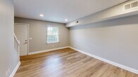 This two-bedroom, two-bathroom residence in Greensboro, NC offers a well-organized two-story layout with thoughtfully designed living spaces. The main floor features a bright living area with light wood-look luxury vinyl plank flooring and a sliding glass door that opens to an outdoor balcony, filling the space with natural light and views of surrounding greenery. The kitchen is outfitted with white cabinetry, marble-style countertops, a double sink, and black appliances including a refrigerator, dishwasher, and electric range, all set atop matching wood-look flooring.

Both bedrooms are carpeted in neutral tones, offering a comfortable feel, and each includes a louvered bi-fold closet door for ample storage. Natural light enters through blinds-fitted windows. One bathroom features a tiled tub-and-shower combo with chrome fixtures, while the second bathroom is a compact, functional space with clean finishes.

Throughout the home, the neutral gray paint palette, white trim, and recessed lighting create a clean and modern ambiance. A staircase connects the two evenly sized floors, and a hallway and additional closet add to the home's practical storage and circulation. The overall layout is efficient and well-suited for everyday living.