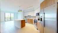 Located at 999 NW 7th St in Miami, FL, this modern single-floor residence offers 4 bedrooms and 2 bathrooms thoughtfully designed with clean lines and contemporary finishes throughout. Large-format porcelain tile flooring flows seamlessly across all rooms, reinforcing the home's cohesive, minimalist aesthetic.

The open-concept kitchen is a standout feature, showcasing two-tone cabinetry with warm wood lower cabinets and crisp white uppers, a white quartz countertop island, stainless steel appliances, and a stylish pendant light cluster. The layout connects effortlessly to the living area, making the space ideal for entertaining.

Multiple bedrooms feature floor-to-ceiling sliding glass doors that open to a balcony with decorative perforated railings, framing impressive views of the Miami skyline and a tranquil waterway. The primary bedroom enjoys dual exposures, maximizing natural light and panoramic outdoor scenery.

The two bathrooms reflect the same modern design language. One features a glass-enclosed walk-in shower with white subway tile, wood-toned vanity, and white quartz countertop. The second includes a soaking tub with tiled surround, dual-sink vanity, and a large framed mirror. Two closets provide practical storage, one fitted with wire shelving systems.