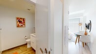 Located at 213 Albany St in Boston's South End neighborhood, this thoughtfully designed single-floor studio maximizes every inch of its layout with smart, modern finishes throughout. The open-plan living area seamlessly integrates the kitchen and sleeping space, creating a functional and cohesive environment. Light hardwood flooring runs throughout, contributing to a bright and airy ambiance, complemented by a large window that allows natural light to fill the space.

The kitchen is outfitted with crisp white high-gloss cabinetry, light quartz countertops, a classic subway tile backsplash, and a full suite of stainless steel appliances including a refrigerator, electric range, built-in microwave, and dishwasher. A single-basin undermount sink with a modern chrome faucet completes the efficient and stylish cooking area.

The living and sleeping space features a built-in Murphy bed system with integrated storage shelving above, offering a versatile and space-conscious solution for everyday living. A large window with blinds provides both natural light and privacy.

The bathroom is clean and contemporary, finished with warm-toned stone-look floor tiles, a frameless glass-enclosed shower, a floating white vanity, and crisp white walls. The overall design of the unit emphasizes minimalism, functionality, and a light, modern aesthetic throughout.