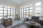 This contemporary single-floor residence is defined by its striking architectural design, highlighted by impressively high ceilings and an abundance of natural light streaming through oversized windows throughout. The open living area serves as the heart of the space, featuring large floor-to-ceiling windows that frame expansive outdoor views and flood the room with daylight, complemented by smooth light wood-style flooring that runs throughout the main areas.

The kitchen is thoughtfully designed with rich wood-grain cabinetry, crisp white quartz countertops, a white subway tile backsplash, and a full suite of stainless steel appliances including a refrigerator, range, and over-the-range microwave. A center island with an integrated sink provides additional prep space and casual seating.

The bedrooms offer plush carpeting underfoot, soaring ceilings, and generous windows that bring in natural light while maintaining privacy. Closet space is well integrated into each room's layout.

Two bathrooms round out the space with consistent modern finishes. The secondary bath features wood-tone cabinetry, a quartz vanity top, and tile-look flooring. The primary bath offers an elongated vanity, a glass-enclosed shower, and coordinating wood-style flooring, creating a clean and functional retreat throughout.