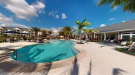 This single-story amenity space embodies the essence of tropical resort living, centered around a striking freeform swimming pool with crystal-clear turquoise water. The expansive pool area is framed by elegant stone pavers and lined with a generous selection of lounge chairs, perfect for relaxing in the sun. Towering palm trees are thoughtfully placed throughout the outdoor space, lending a lush, tropical atmosphere that complements the warm, sun-drenched surroundings.

Adjacent to the pool, a sophisticated clubhouse serves as the anchor of the community, featuring a classic architectural design with a pitched roof, white-trimmed windows, and covered outdoor seating areas. The building's exterior seamlessly connects indoor and outdoor living, with large glass openings that invite natural light and views of the pool and landscaped grounds.

Vibrant tropical plantings, including ornamental shrubs and colorful flowers, accent the hardscaped areas, adding life and color to the environment. Fire or water features near the pool's edge provide additional visual interest and ambiance. The overall setting conveys a sense of spaciousness and leisure, designed to offer residents a private, resort-caliber outdoor experience beneath open blue skies.