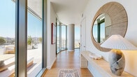 Located at 3401 S La Cienega Blvd in Los Angeles, this thoughtfully designed 3-bedroom, 2-bathroom residence offers a compelling blend of modern architecture and elevated urban living. The open-concept living and dining area is defined by dramatic floor-to-ceiling glass walls that frame sweeping panoramic views of the Los Angeles hillsides and cityscape, flooding the interiors with abundant natural light. Warm hardwood flooring flows throughout, complementing the clean white walls and contemporary aesthetic. A distinctive curved concrete column anchors the dining area, adding an architectural focal point to the space. The living room features built-in cabinetry and generous proportions ideal for entertaining. The outdoor terrace extends the living space further, offering a furnished lounge area with unobstructed open-sky views — perfect for enjoying the Southern California climate. The primary bedroom is comfortably scaled, while the two bathrooms are finished with warm wood vanities, illuminated mirrors, and striking gold-and-white checkered tile flooring. The full bath includes a soaking tub with wall-to-wall square tile surround. A hallway with clean white panel doors and dedicated closet storage rounds out this well-appointed residence.