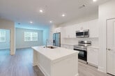 Located at 100 Oakbrook Drive in McDonough, GA, this well-appointed one-bedroom, one-bathroom unit offers a thoughtfully designed single-floor layout. The open-concept living area seamlessly combines the kitchen, dining, and living spaces into one bright, cohesive environment. The kitchen is a standout feature, showcasing crisp white cabinetry, a large center island with an undermount sink, stainless steel appliances including a French door refrigerator, electric range, and over-the-range microwave, all set against light wood-style flooring that extends throughout the unit. Recessed lighting keeps the space bright and modern.

The bedroom is a comfortable retreat with a ceiling fan, a generous window with outdoor greenery views, and direct access to a well-sized walk-in closet equipped with wire shelving for organized storage. The full bathroom features a dual-sink vanity with white countertops and modern hardware, a tub-shower combination with tiled surround, and the same consistent wood-style flooring. Additional practical spaces include a pantry, laundry area, and utility room. The clean, neutral color palette and modern finishes give the entire unit a fresh, move-in-ready feel.