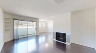 Located in the desirable West Hollywood neighborhood of Los Angeles, this well-designed one-bedroom, one-bathroom residence offers a thoughtful layout across a single floor. The open living room is a standout, featuring rich dark hardwood floors, a classic fireplace with tile surround, and a ceiling fan overhead. Built-in shelving adds functional character to the space, while large sliding glass doors open to a balcony that frames views of the surrounding Los Angeles hillside. Abundant natural light fills the room throughout the day. The kitchen is efficiently designed in a galley configuration, outfitted with warm wood cabinetry, granite countertops, tile flooring, and stainless steel appliances including a gas range and refrigerator. The spacious primary bedroom continues the hardwood flooring and includes a mirrored sliding-door closet, with a window offering additional natural light and outdoor views. The bathroom features tile flooring, a wood vanity with granite countertop, and a tub-shower combination. Clean white walls throughout the residence create a bright, neutral backdrop, lending the space a fresh and modern ambiance ideal for comfortable city living.